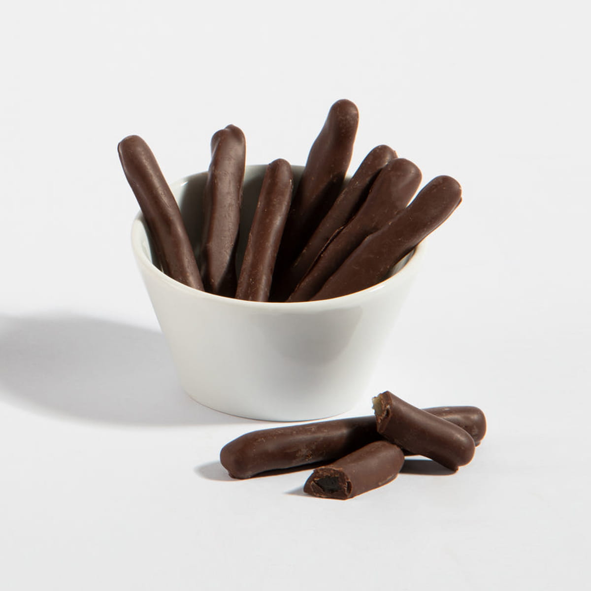 Charles Chocolates Chocolate Covered Lemon Peel sticks in a bowl with one cut in half in the foreground