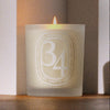 Diptyque 34 Boulevard Saint Germain Candle (300 g) - product shown lit on wooden counter with a photo grain. 