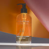 Lifestyle shot of Eau d'Italie Frankincense & Myrrh Liquid Soap (300 ml) with orange, gray and pink paper in the background