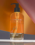 Lifestyle shot of Eau d'Italie Frankincense & Myrrh Liquid Soap (300 ml) with orange, gray and pink paper in the background