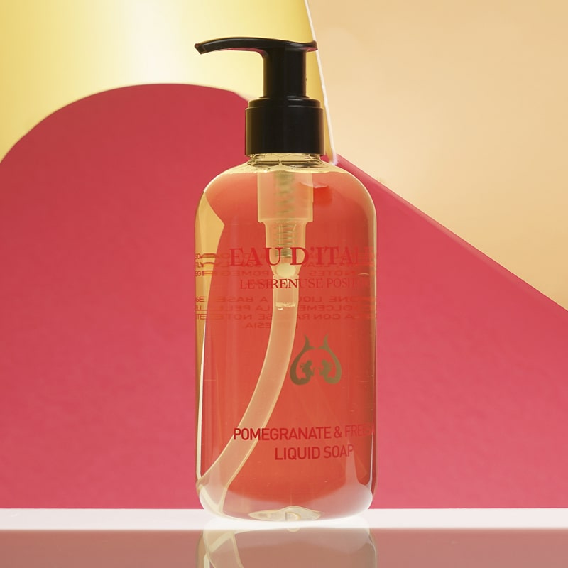 Lifestyle shot of Eau d&#39;Italie Pomegranate &amp; Freesia Liquid Soap (300 ml) with red and yellow paper in the background