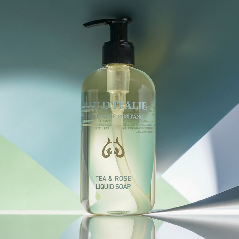 Lifestyle shot of Eau d&#39;Italie Tea &amp; Rose Liquid Soap (300 ml) with green and blue paper in the background