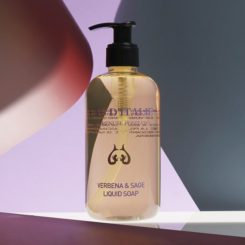 Lifestyle shot of Eau d&#39;Italie Verbena &amp; Sage Liquid Soap (300 ml) with purple and dark gray paper in the background