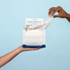 Model with opened box of Clean Skin Club Clean Towels XL pulling sheet out
