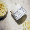 Lifestyle shot of Santa Maria Novella Idralia Face Cream (50 ml) with white roses in the background