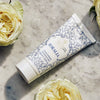 Lifestyle shot Santa Maria Novella Idralia Exfoliating Cream (100 ml) with white roses in the background