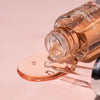 Close up shot of Cinq Mondes Radiance Precious Elixir Facial Oil (0.50 oz) showing serum spilling from bottle and dropper