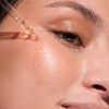 Close up of model using Cinq Mondes Radiance Precious Elixir Facial Oil on cheek