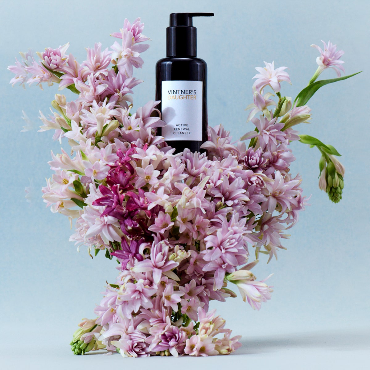 Lifestyle shot of Vintner&#39;s Daughter Active Renewal Cleanser (115 ml) sitting among pink flowers