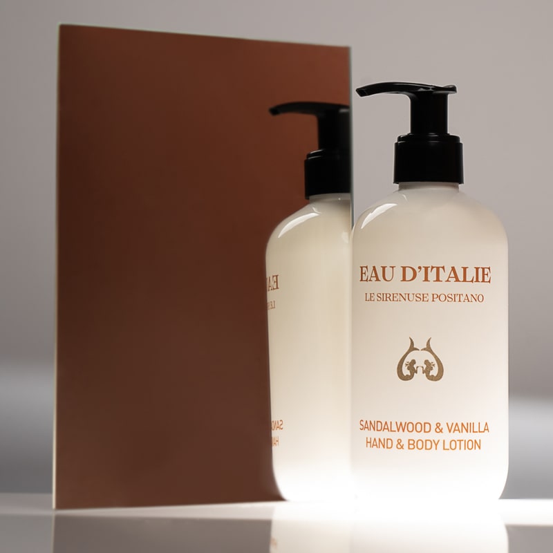 Lifestyle shot of Eau d’Italie Sandalwood & Vanilla Hand & Body Lotion (300 ml) in front of mirror with brown background reflection