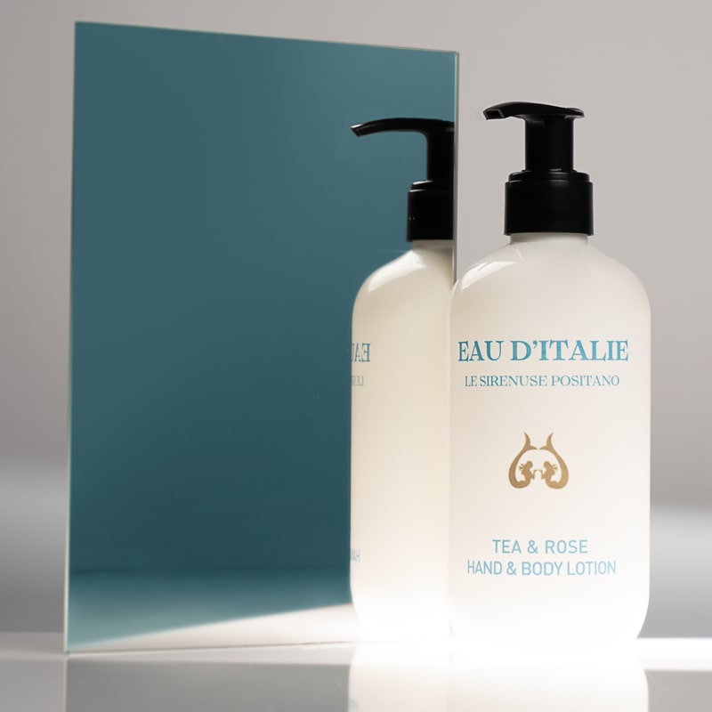 Lifestyle shot of Eau d’Italie Tea &amp; Rose Hand &amp; Body Lotion (300 ml) in front of mirror with blue background reflection