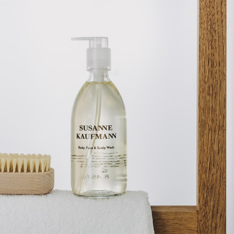 Susanne Kaufmann Body, Face &amp; Scalp Wash - Product displayed on table with towel and brush