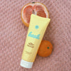 Bask Sunscreen SPF 30 Lotion Sunscreen (3.4 oz) next to a sliced grapefruit and an orange on a textured pink background.