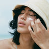 Model applying Bask Sunscreen SPF 30 Lotion Sunscreen to her face