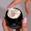 Close up of model holding opened jar of Odacite Jojoba Pearls Daily Hydra-Exfoliant (50 ml)