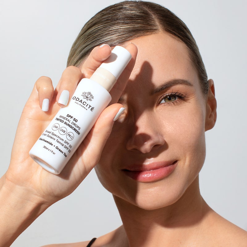 Model holding in her hand Odacite SPF 50 Flex-Perfecting™ Mineral Drops Tinted Sunscreen (30 ml) - ONE