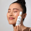 Model holding bottle of Odacite SPF 50 Flex-Perfecting™ Mineral Drops Tinted Sunscreen (30 ml) - TWO
