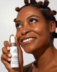 Model holding bottle of Odacite SPF 50 Flex-Perfecting™ Mineral Drops Tinted Sunscreen - 30 ml - FOUR 