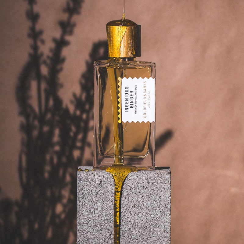 Goldfield &amp; Banks Ingenious Ginger Perfume - Perfume bottle on concrete with honey dripping on it