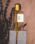 Goldfield & Banks Ingenious Ginger Perfume - Perfume bottle on concrete with honey dripping on it