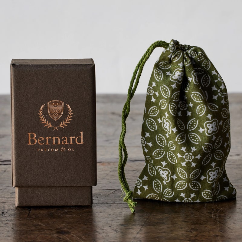 Bernard Parfum Antheia Roll On Parfum Ol Bijou - Product displayed on wood table wrapped in cloth with packaging