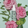 Lifestyle shot of Santa Maria Novella Acqua di Rose Gel Cream (50 ml) with pink roses and leaves in the background