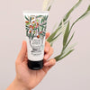 Fragonard Parfumeur Olive Oil Hand & Foot Cream - Hand holding product with olive branch behind it