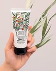 Fragonard Parfumeur Olive Oil Hand & Foot Cream - Hand holding product with olive branch behind it