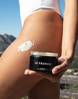 Le Prunier Plumbody - Lifestyle photo of model holding body cream container, with swatch on leg