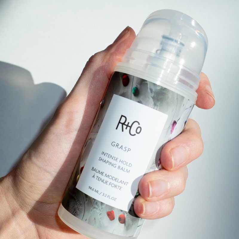 R+Co Grasp Intense Hold Shaping Balm - Product shown in models hand