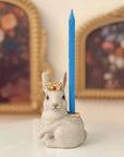 Camp Hollow Royal White Rabbit Cake Topper - Product displayed with candle