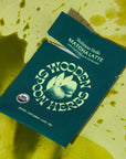 Wooden Spoon Herbs Mushroom Vanilla Matcha Latte Sachets - Beauty shot, sachet shown on green background