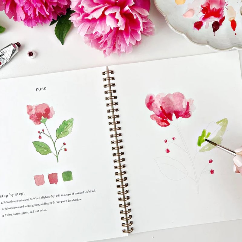 Emily Lex Studio Flowers Watercolor Workbook - open workbook showing watercolor illustration and hand holding paint brush