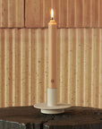 Carriere Freres Cedar 8" Taper Candles - lit candle in candle holder on wood table