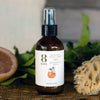 8 Days Botanicals Joy Botanical Room Spray - bottle next to sponge, orange, and flowers