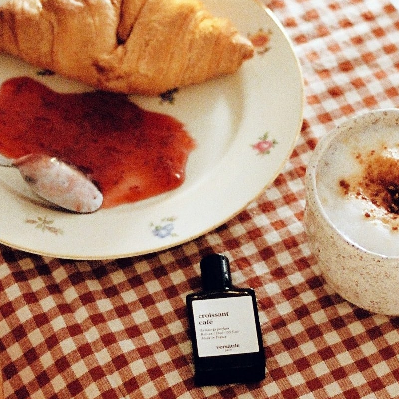Versatile Paris Croissant Cafe Extrait de Parfum on table beside cup of coffee and croissant with jam