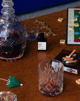 Versatile Paris Gueule de Bois (Hangover) Extrait de Parfum on a table with Spirits and board games and an astray full of cigarette butts