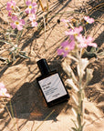 Versatile Paris Sea, Sud & Sun (Sea, South & Sun) Extrait de Parfum shown on sand by wildflowers