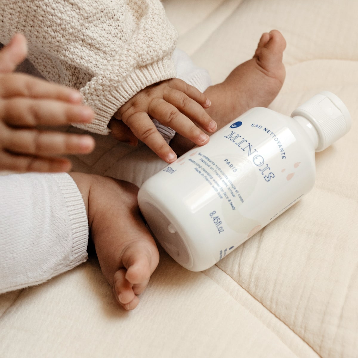 Minois Paris Eau Nettoyante (Moisturizing Cleansing Water) (250 ml) - product shown next to baby feet. 