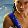 Augustinus Bader The Rich Conditioner - lifestyle shot of model in water holding conditioner bottle