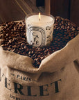 Lifestyle shot of Diptyque Cafe (Coffee) Candle (190 g) sitting in a Verlet Paris Cafe sack opened and filled with whole coffee beans