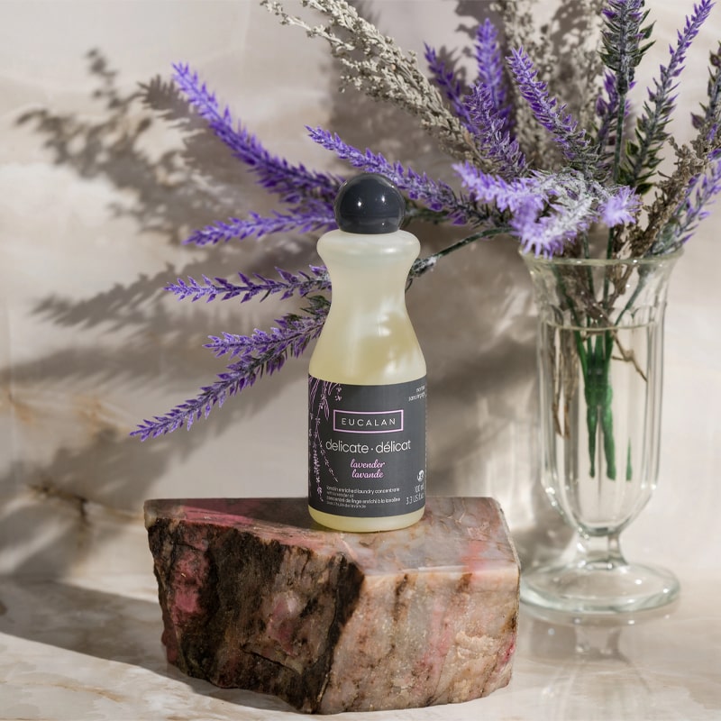 Eucalan Lavender Delicate Wash - Lifestyle shot of Product on stone next to glass vase with lavender flowers