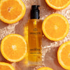 Odacite C-Glow Hydra-Firm Body Oil - Beauty shot, product shown with oranges