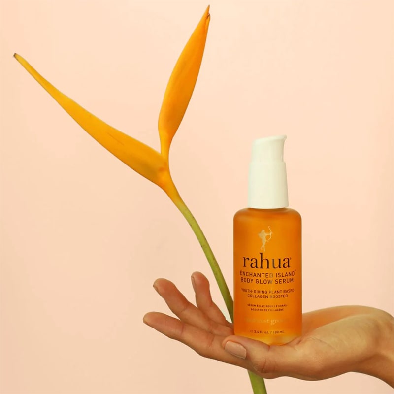 Rahua Enchanted Island Body Glow Serum - Product shown in models hand with flower in background