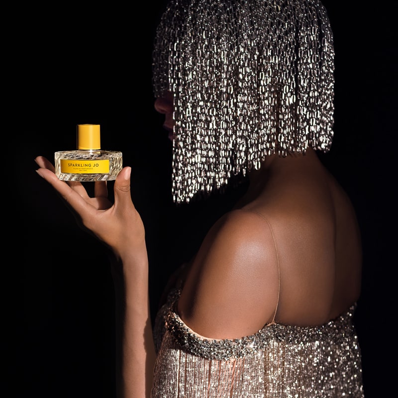 Model with sparkling/glitter wig and dress holding Vilhelm Parfumerie Sparkling Jo Eau de Parfum (50 ml)