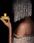 Model with sparkling/glitter wig and dress holding Vilhelm Parfumerie Sparkling Jo Eau de Parfum (50 ml)