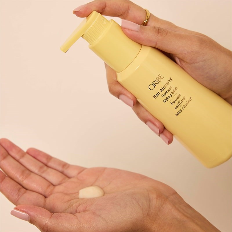 Oribe Hair Alchemy Heatless Styling Balm - Model shown dispensing product into hand