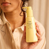 Oribe Hair Alchemy Heatless Styling Balm - Before and after photos- Closeup of product in models hand