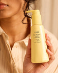 Oribe Hair Alchemy Heatless Styling Balm - Before and after photos- Closeup of product in models hand
