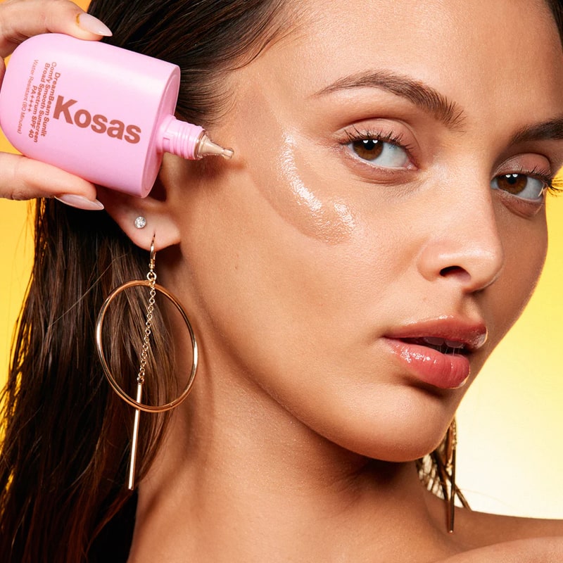 Kosas DreamBeam Sunlit Comfy Smooth Sunscreen SPF 40 - Model shown applying product to face